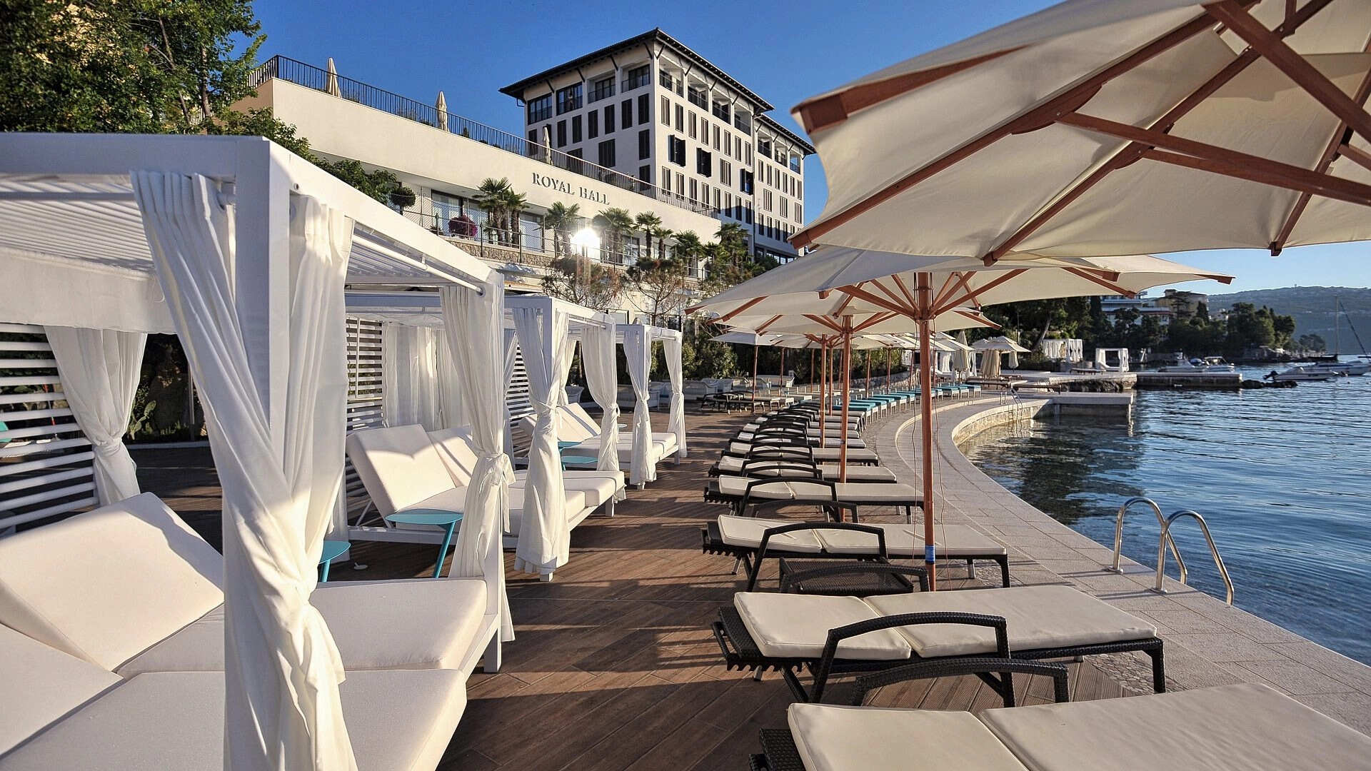 Sunbeds and parasols on a stylish Adriatic beach lounge overlooking Kvarner Bay